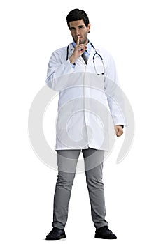 A full-length male doctor shows a sign of silence on a White background