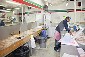 Full-length of male employee organizing meat in supermarket