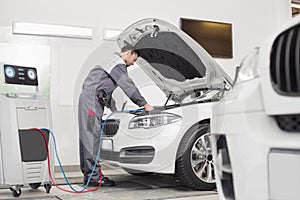 Full length of male engineer examining car in automobile repair shop