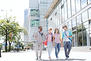 Full-length male and female friends walking on city street