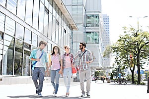 Full-length male and female friends walking on city street