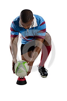Full length of male rugby player keeping ball on tee