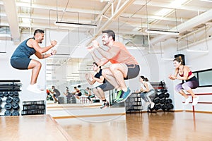 Trainer Doing Tuck Jumps With Clients In Health Club photo