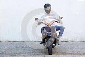 Full length of man in helmet riding a moped on road