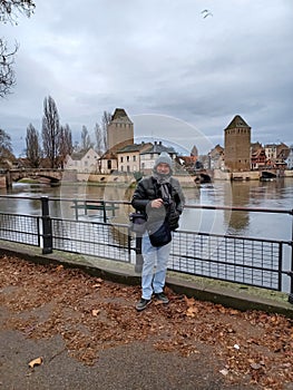 Full length mature man at the medieval bridge Ponts Couverts and barrage Vauban, evening scene of Strasbourg