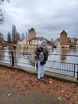 Full length mature man at the medieval bridge Ponts Couverts and barrage Vauban, evening scene of Strasbourg