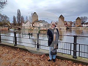 Full length mature woman at the medieval bridge Ponts Couverts and barrage Vauban, evening scene of Strasbourg