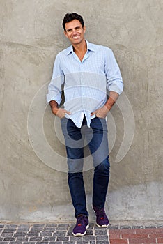 Full length middle age man smiling and leaning against wall