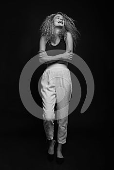 Full-length monochrome portrait of young woman posing over black background. Fashion studio shot.