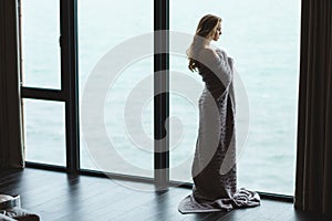 Full length of pensive woman in knitted coverlet enjoying view