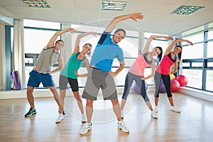 Full length of people doing power fitness exercise at yoga class