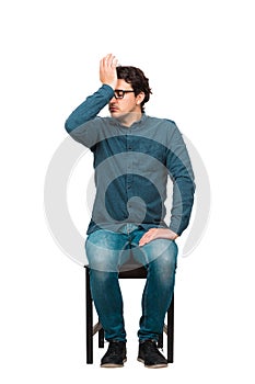 Full length of pessimistic businessman, eyes closed facepalm gesture, punching himself to forehead, seated on a chair isolated on photo