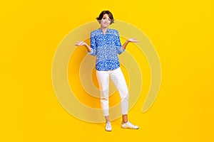 Full length photo of adorable unsure woman dressed blue blouse shrugging shoulders isolated yellow color background