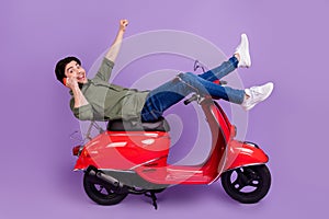 Full length photo of amazed brunette man winner rider phone talk crazy isolated on purple color background