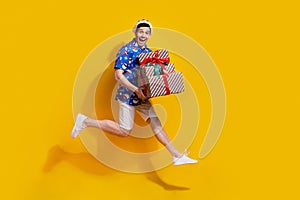 Full length photo of astonished energetic guy jump run hold pile stack giftbox empty space isolated on yellow color