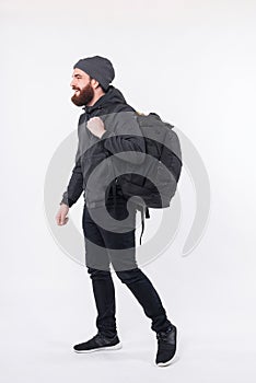 Full length photo of bearded man walking over white background with backpack