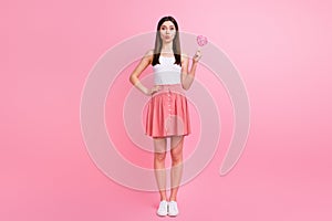 Full length photo of charming funny lady send air kisses hold big heart shape lollipop on stick good mood wear white