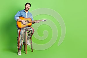 Full length photo of cheerful cool guy wear denim jacket sing enjoy guitar music empty space isolated green color