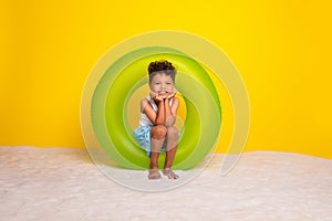 Full length photo of cheerful dreamy little boy dressed white shirt sitting inflatable ring empty space  yellow