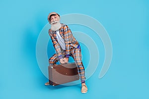 Full length photo of cheerful man pensioner wear checkered costume rising heavy baggage empty space isolated blue color