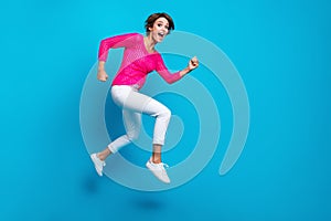 Full length photo of cheerful positive woman wear knitted neon shirt jumping high running empty space isolated blue