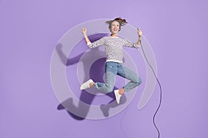 Full length photo of cheerful young woman wear casual outfit jumping holding microphone isolated violet color background