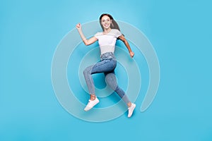 Full length photo of cheerful youth running wearing white t-shirt denim jeans sneakers isolated over blue background