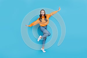 Full length photo of childing fooling woman wear orange sweater having fun arms sides isolated blue color background