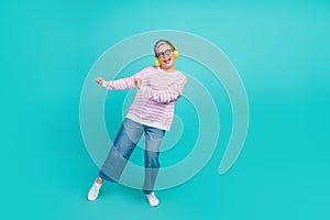 Full length photo of cool funky woman dressed pink pullover earphones dancing empty space isolated teal color background