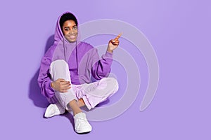 Full length photo of cool millennial lady sit ndex promo wear hoodie trousers shoes isolated on purple background