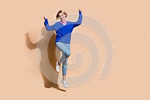 Full length photo of crazy delighted person raise fists success jump empty space isolated on beige color background