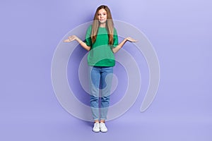 Full length photo of doubtful unsure girl dressed green t-shirt shrugging shoulders isolated purple color background
