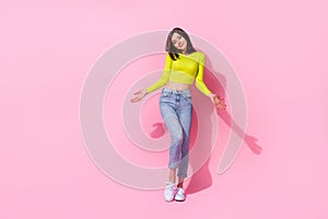 Full length photo of doubtful unsure lady wear yellow top shrugging shoulders empty space isolated pink color background