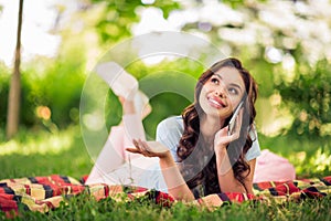 Full length photo of dreamy nice joyful happy woman lie blanket talk smart phone vacation relax outside outdoors park