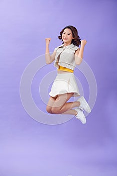 Full length photo of ecstatic girl jump win raise fists scream  over purple color background