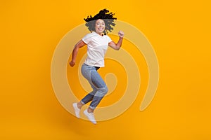 Full length photo of excited cheerful woman wear white t-shirt jumping high running empty space isolated yellow color