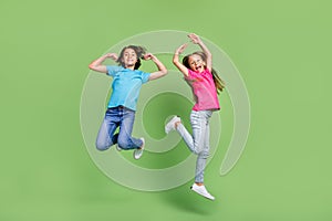 Full length photo of excited funky friends wear t-shirts jumping high enjoying sports isolated green color background