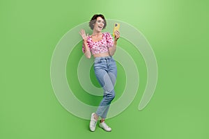 Full length photo of excited funky girl dressed print top video call modern device isolated green color background