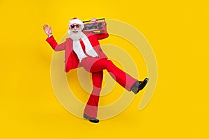 Full length photo of excited funky santa dressed red suit tie walking enjoying boom box music empty space isolated