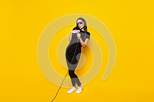 Full length photo of excited positive girl arm hold mic excited singing isolated on yellow color background