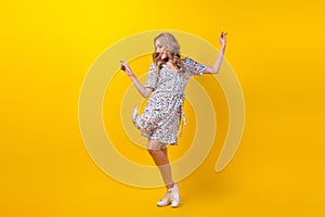 Full length photo of excited sweet woman dressed flower print sarafan having fun dancing isolated yellow color