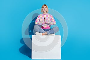 Full length photo of focused appreciative girl wear colorful pullover sit on platform in meditation pose isolated on