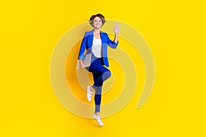 Full length photo of friendly sweet woman wear blue jacket holding modern device waving arm jumping high  yellow