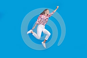 Full length photo of funky cheerful lady dressed print shirt jumping high running empty space isolated blue color