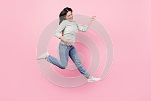 Full length photo of funky cheerful young woman jump up play imagine guitar isolated on pink color background