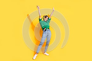 Full length photo of funky cool lady wear green shirt earphones enjoying songs dancing isolated yellow color background