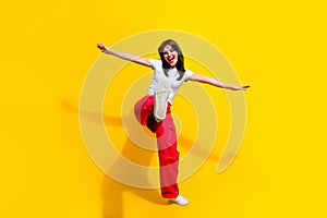 Full length photo of funky cool woman dressed white t-shirt arms sides walking dancing discotheque isolated yellow color