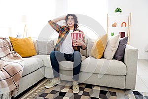 Full length photo of funky excited guy dressed checkered shirt enjoying pop corn watching intrigue movie indoors house