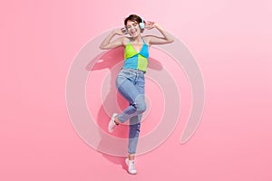 Full length photo of funky girl dancing and listening her brand new wireless bluetooth headphones sony isolated on pink