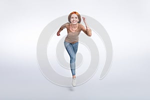 Full length photo of funky pretty redhair woman beige shirt jumping high running fast isolated white color background